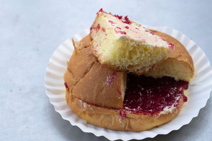 A soft, bap-like bun, sliced in half, then slathered with salty butter and fruit jam