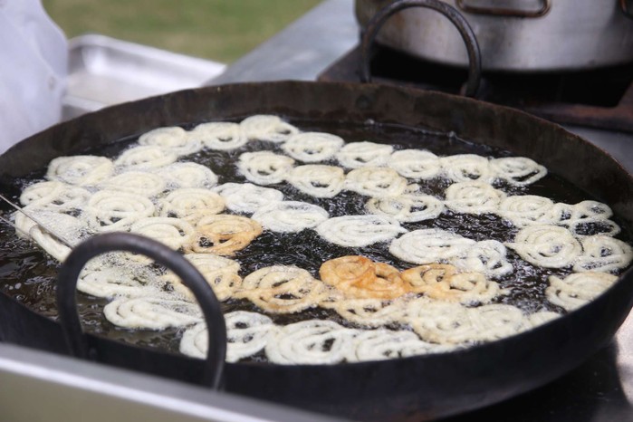 Jangiri spiral sweets frying in a large pan